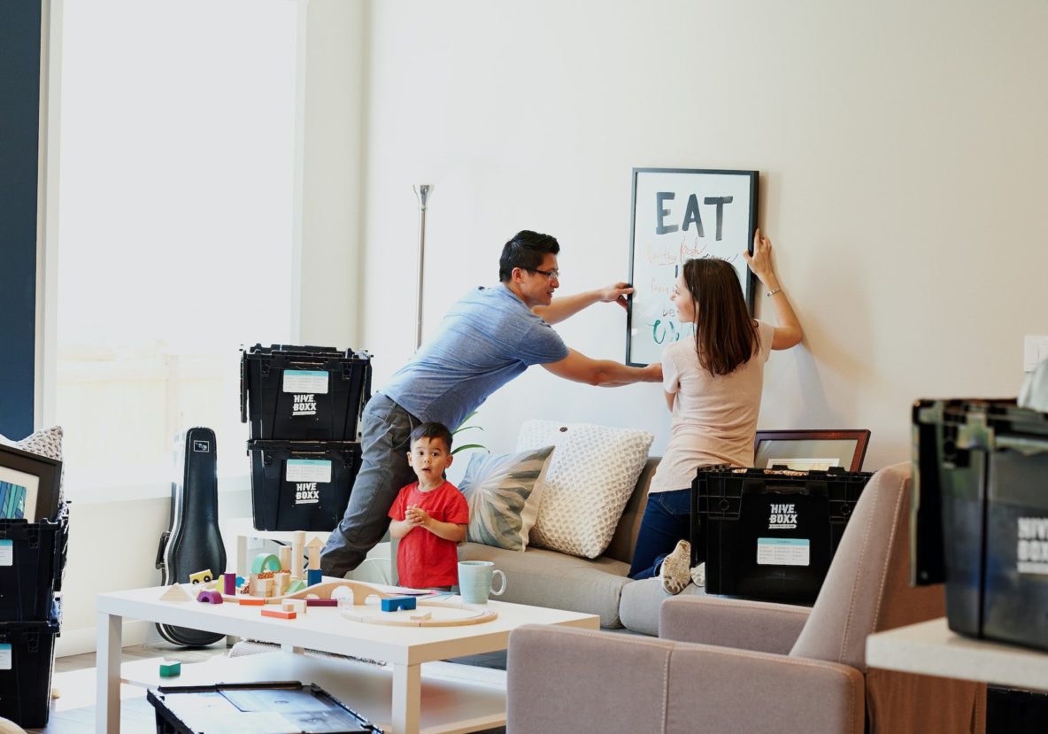 Married couple hanging up a picture in their new home